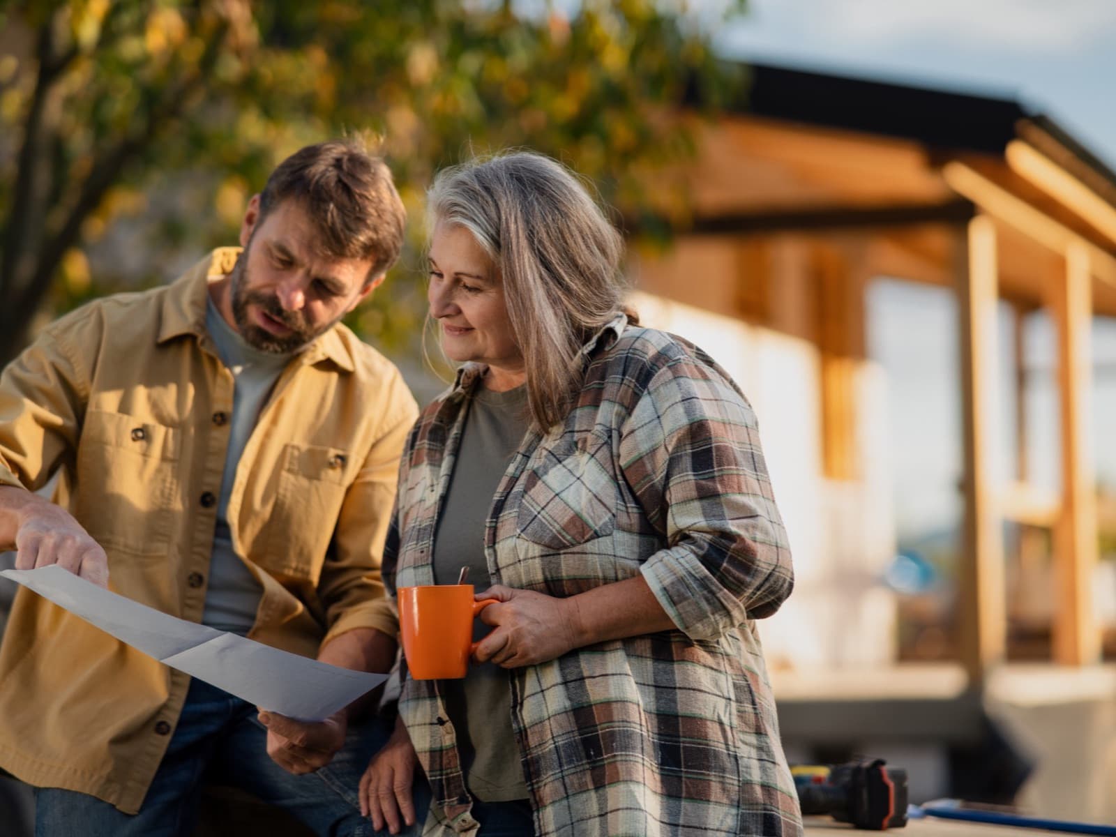 Couple reviewing plans with coffee outdoors.
