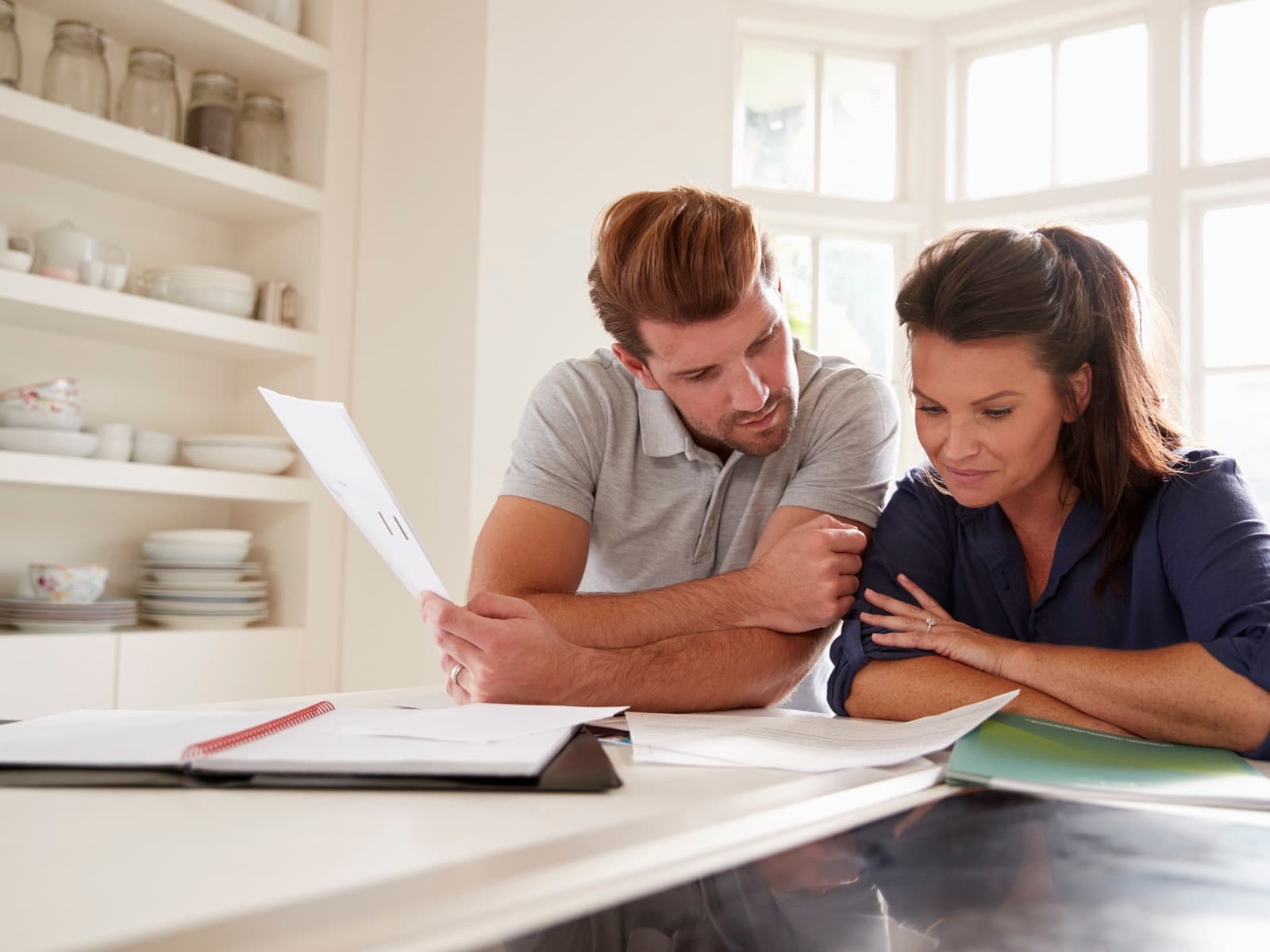 Couple reviewing documents at kitchen counter.