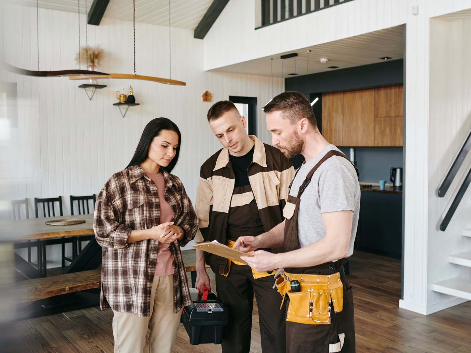 Woman discussing plans with two repairmen.
