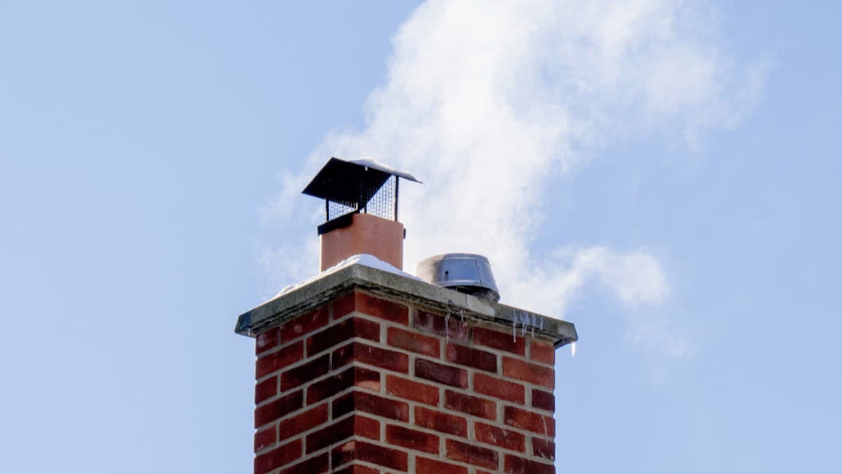 A capped brick chimney against a blue sky