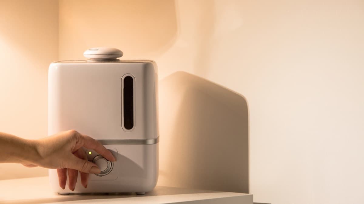 A hand adjusting the knob on a white cool-mist humidifier