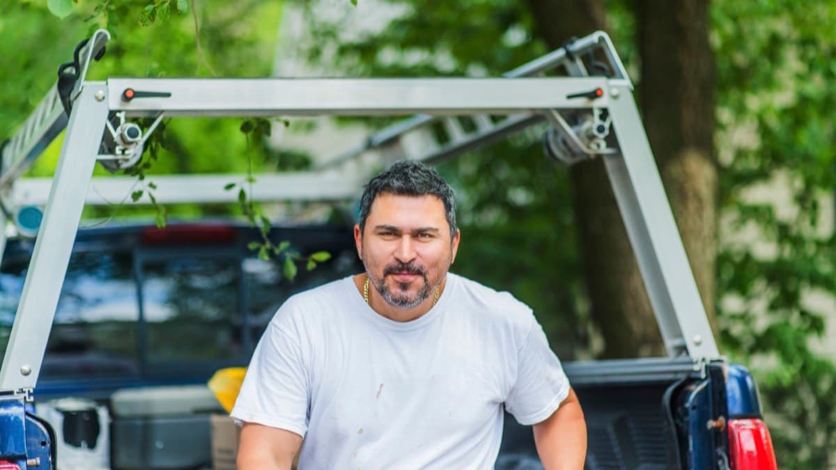 A contractor at the tailgate of his pickup, a ladder rack over the bed