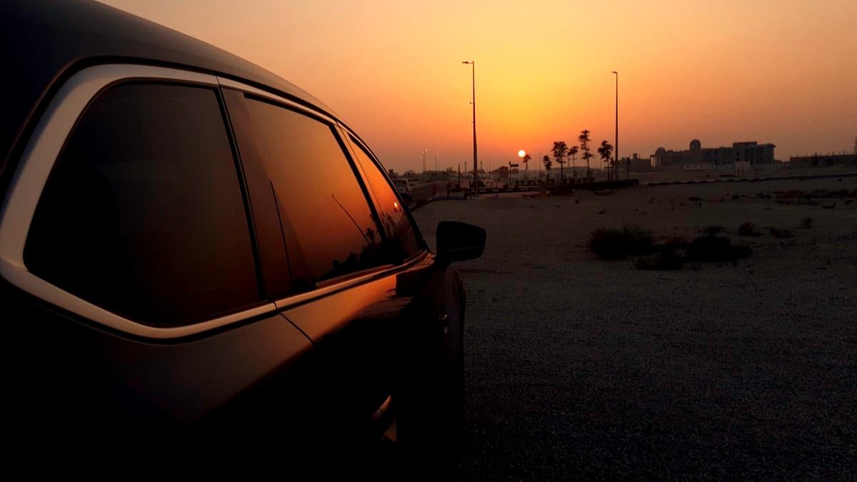 A car pulled over and parked at the roadside as the sun sets