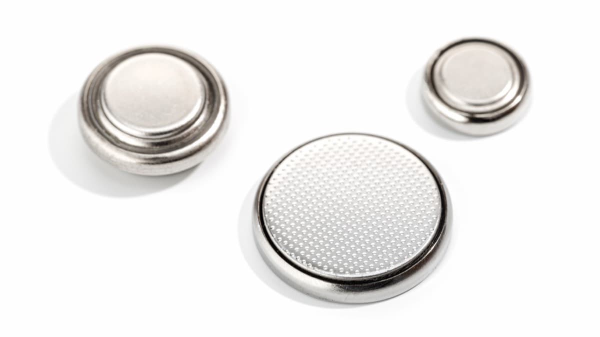 Three silver coin batteries of different sizes on a white surface
