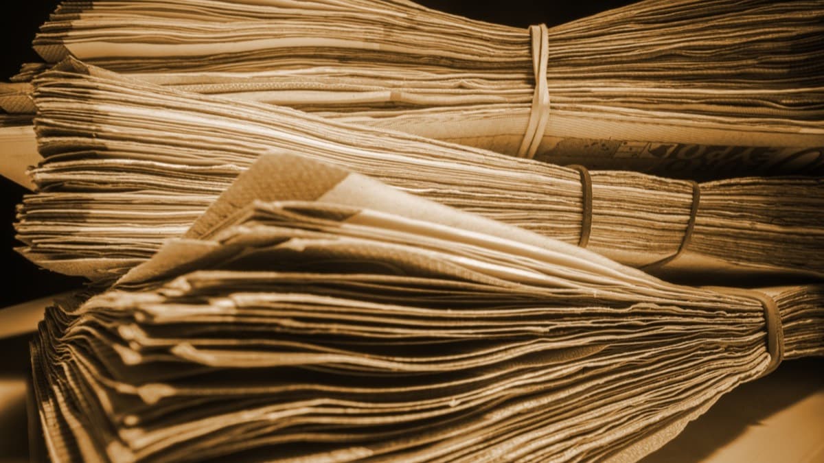 Bundles of old yellowed newspapers tied with rubber bands