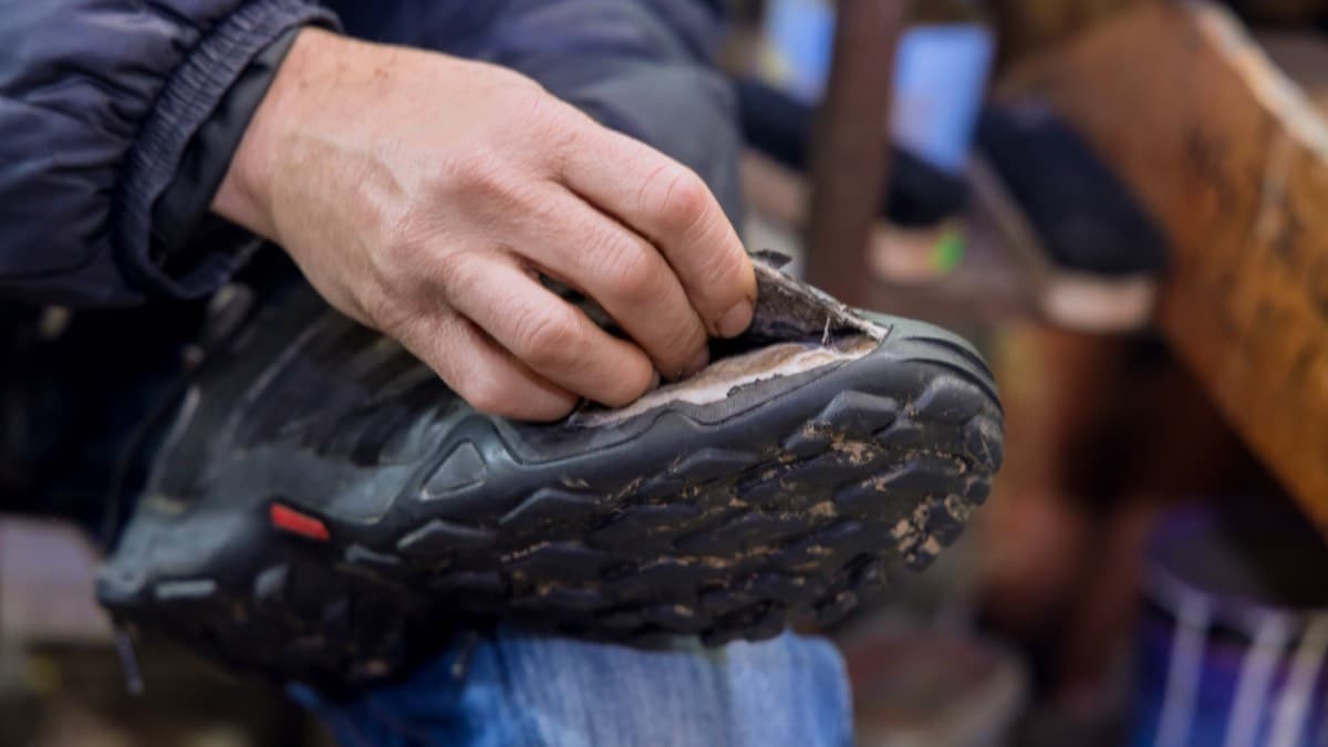 A worker's hand on a dusty, mud-caked work boot