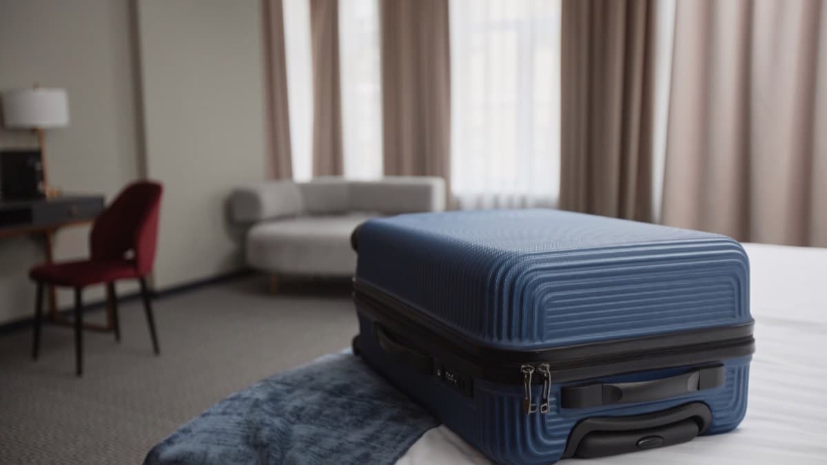 A packed suitcase on the bed of a hotel room
