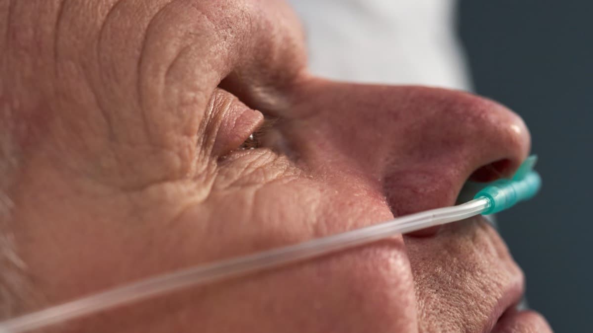 A close-up of an older man breathing through a nasal oxygen cannula
