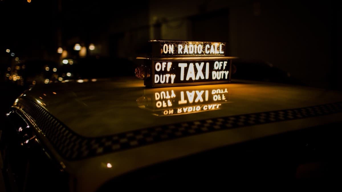 A lit taxi roof sign on a checkered cab at night