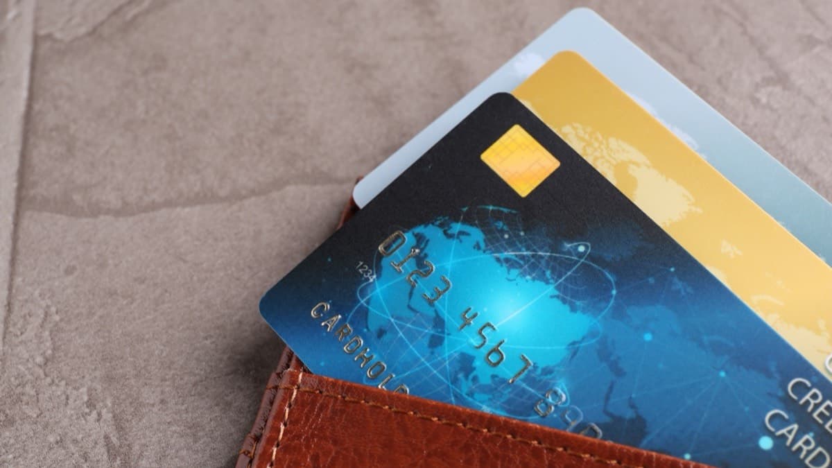 Three payment cards tucked into a brown leather wallet