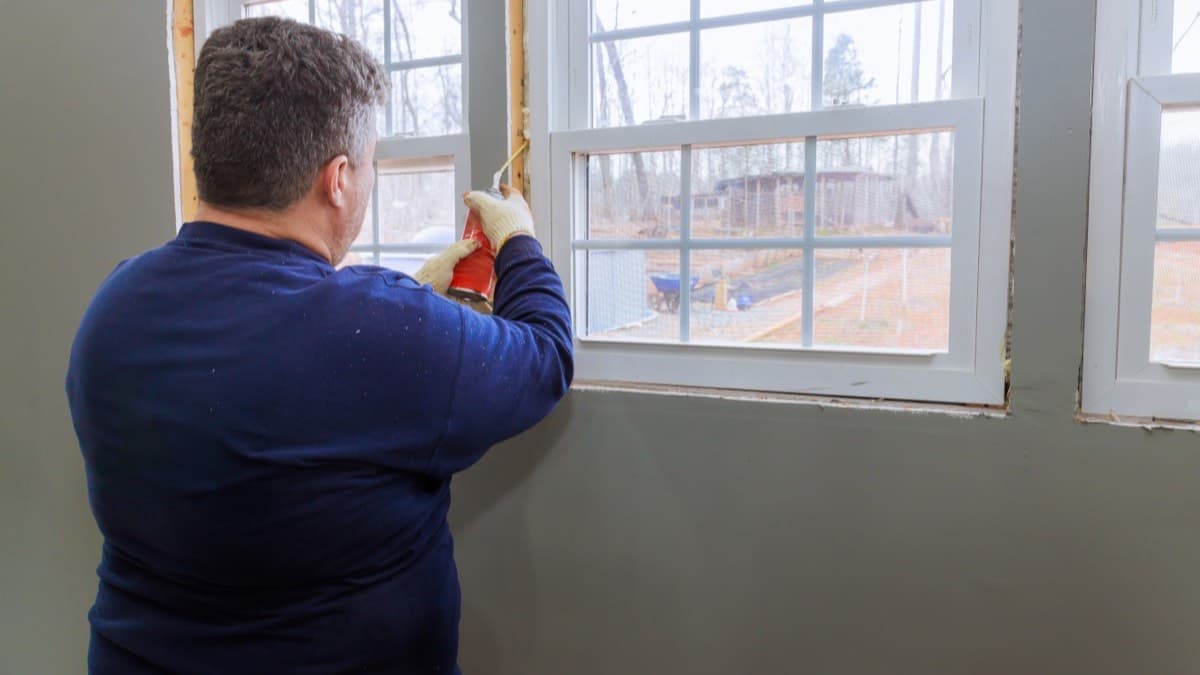 An installer sealing a new double-hung window with foam