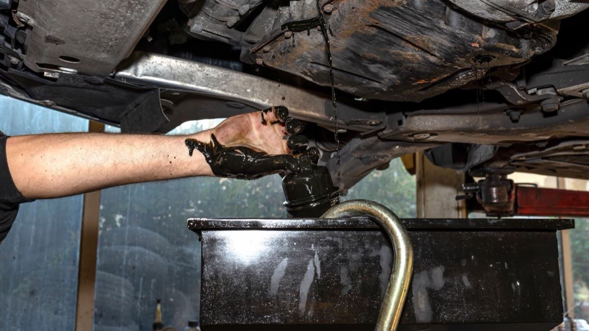 Used motor oil draining from a car's oil filter into a collection pan