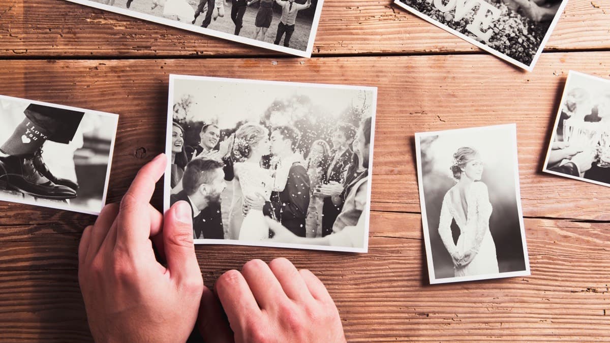 Black-and-white family wedding prints laid out face up on a wooden table