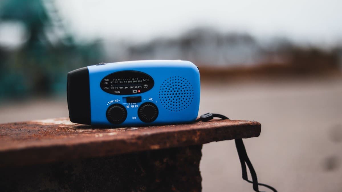 A blue hand-crank radio with a weather band, AM and FM dial on a ledge