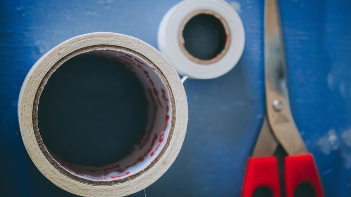 Two rolls of tape and a pair of scissors on a blue table