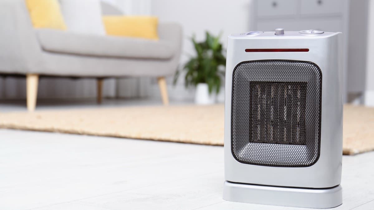 A small ceramic space heater on a bare floor with open space between it and the couch