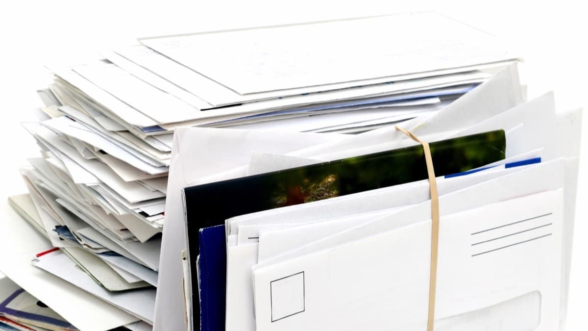 A tall stack of envelopes and a catalog held together with a rubber band