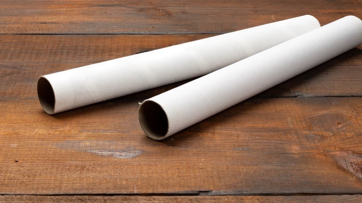 Two white cardboard storage tubes on a wooden table