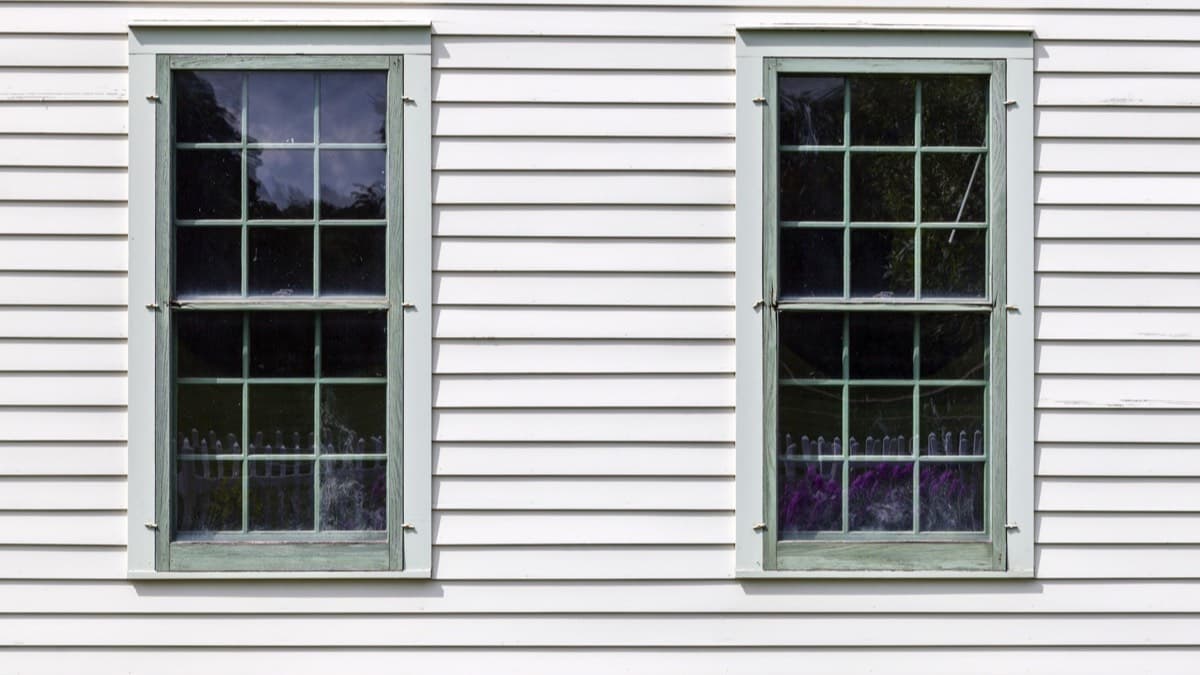 Two old double-hung windows on a white clapboard house