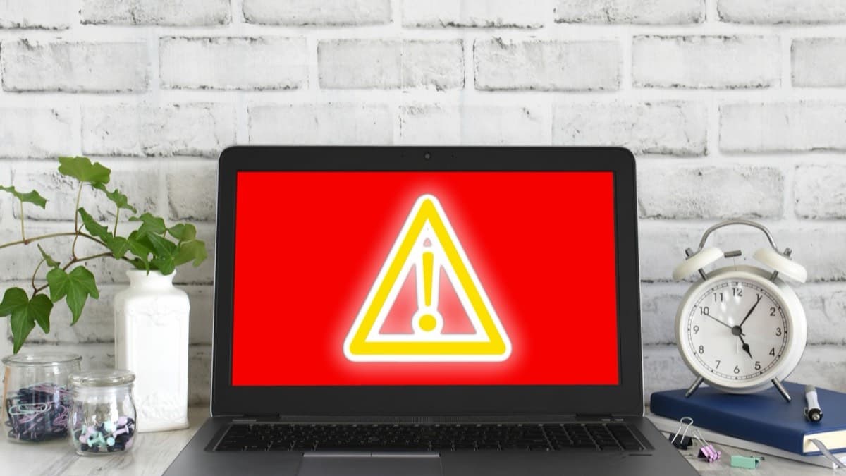 A laptop screen filled with a red warning sign