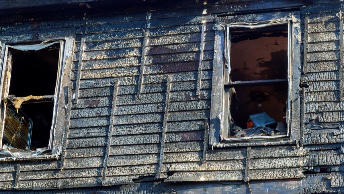 Charred clapboard siding and burned-out windows on a house after a fire