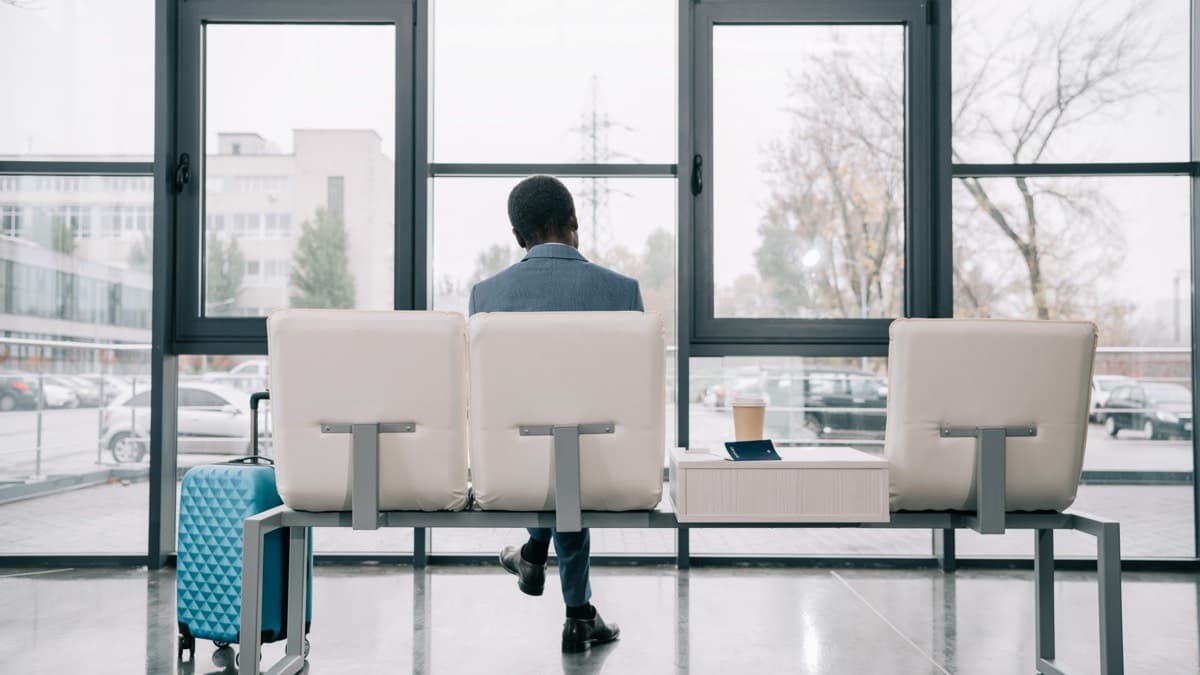 A traveler with a suitcase waiting in an airport terminal