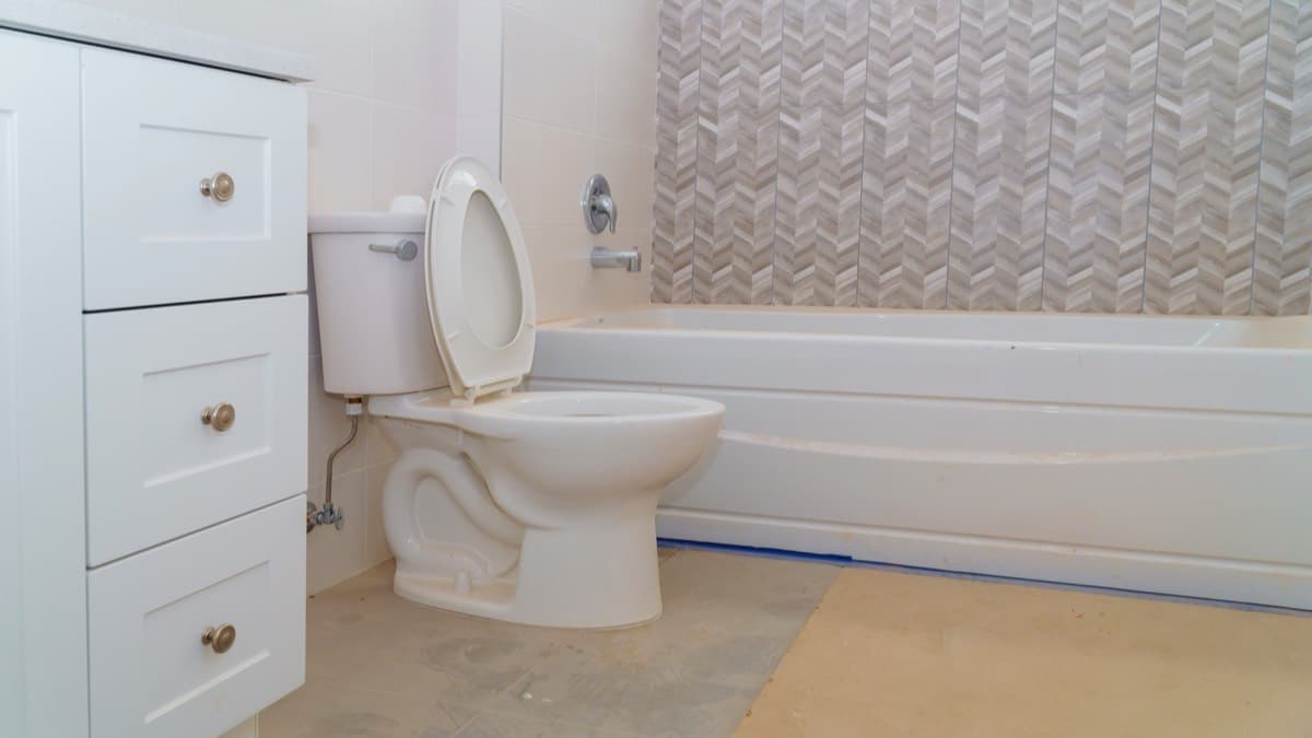 A two-piece toilet beside a white vanity in a newly renovated bathroom