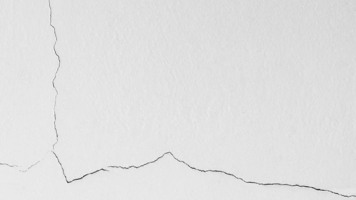 A hairline settlement crack branching across a white painted wall
