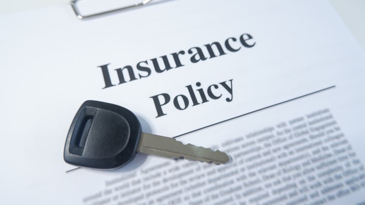 A car key resting on a printed insurance policy on a clipboard