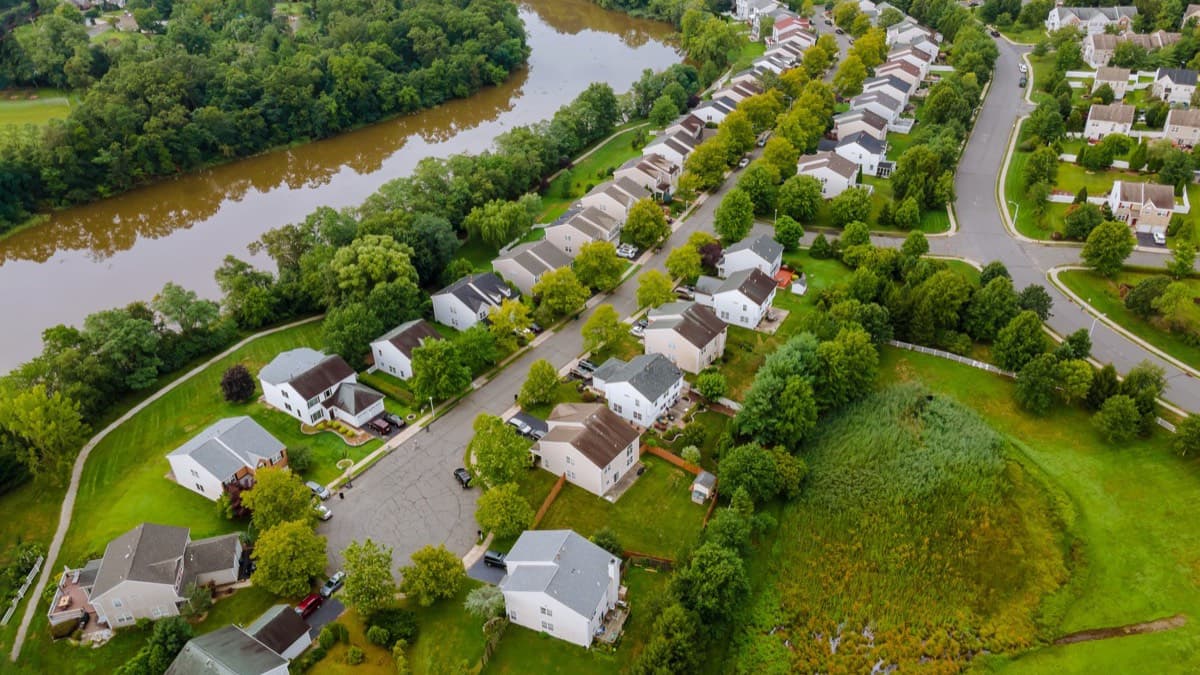 An aerial view of a suburban neighborhood built along the bank of a winding river