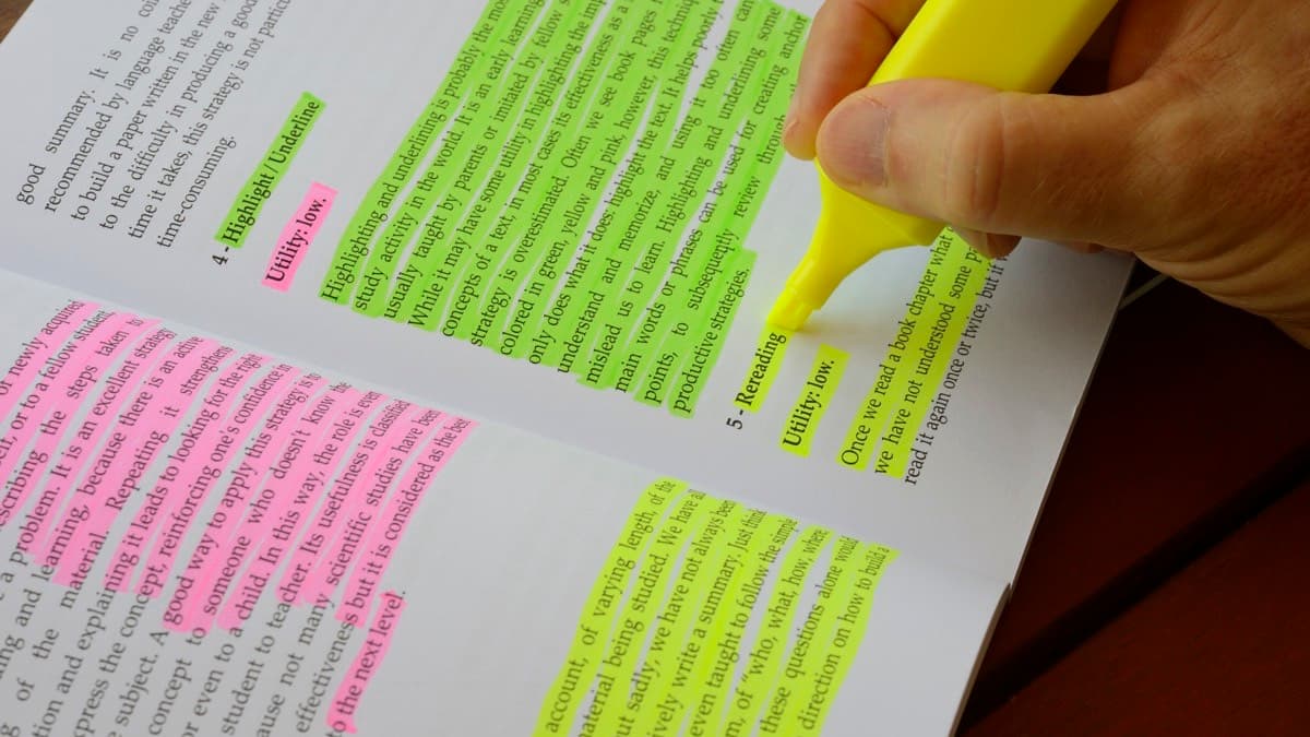 A hand marking printed findings with highlighters in three colors